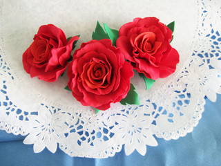 Artificial red roses on a white background. Photo of creative works.