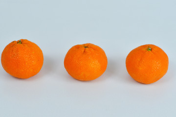three orange tangerines on a white background