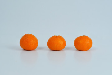 three orange tangerines on a white background