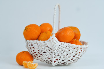tangerines in a white woven basket against a white background