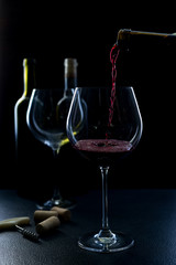  glass of red and pink wine on a black background. Wine list menu. Close up of the power of glasses and bottles in low key