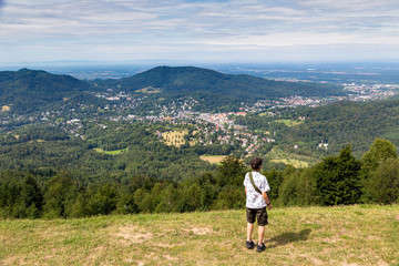 Fototapeta na wymiar Teenage boy looking at the view of the town of Baden Baden from Murkur mountain in the Black Forest in Germany