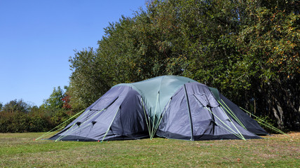 Big family camping tent on the edge of the meadow in the forest campsite, on a summer sunny day . © Yols