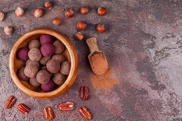 Homemade Raw Vegan Cacao Energy Balls in Wooden Bowl on Brown Marble Background. Healthy Chocolate Candy from Nuts and Dates. Concept of Natural Vegetarian Handmade Dessert. Top View. Copy Space