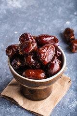 Tasty palm dates in bawl on gray stone table Vertical.