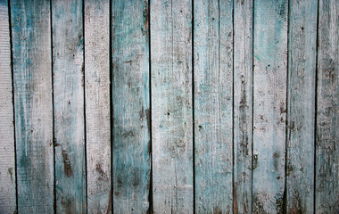 Worn old rough-hewn pine vertical wooden boards with scratches and faded light blue paint. Abstract wooden background.