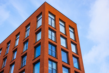 View of a new residential rectangular modern red brick house with classic windows.