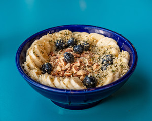 A bowl of steel cut oatmeal topped with banana, blueberries and grains