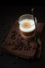 Top view on thermo glass cup of latte coffee on dark wooden table. Morning beverage