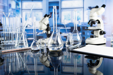 Science laboratory. Beakers, test-tubes and microscope on glass table in the laboratory.