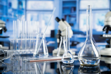 Science laboratory. Beakers, test-tubes and microscope on glass table in the laboratory.