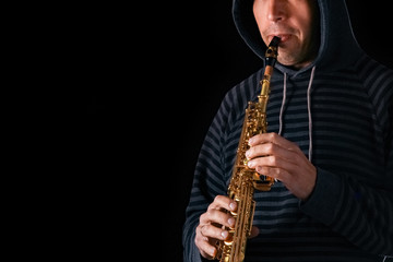 Naklejka premium soprano saxophone in the hands of a guy on a black background