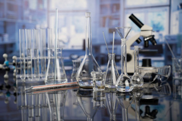 Science laboratory. Beakers, test-tubes and microscope on glass table in the laboratory.