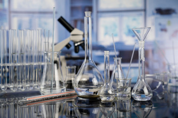 Science laboratory. Beakers, test-tubes and microscope on glass table in the laboratory.