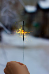 burning sparkler in hand on a winter background