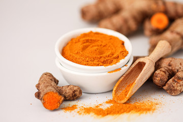 Turmeric root and turmeric powder on a white background