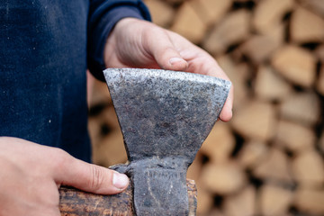A man checks an ax blade. Holds an ax in his hands. Close up