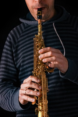 Naklejka premium soprano saxophone in the hands of a guy on a black background