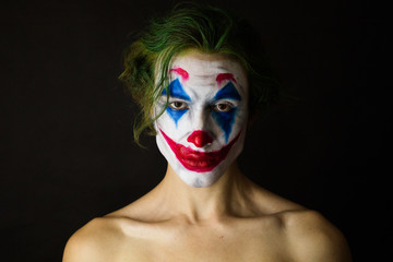 Portrait of a man with clown makeup and green hair, cosplay.