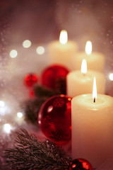 4 weiße Kerzen mit roter Weihnachtsdekoration in verträumter Athmosphäre