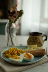 Light breakfast of corn, cheese, sausages and eggs with a sauce