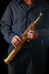 Fototapeta premium soprano saxophone in the hands of a guy on a black background