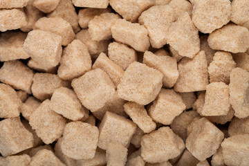 Close-Up shot of natural brown unrefined sugar cubes on white background.