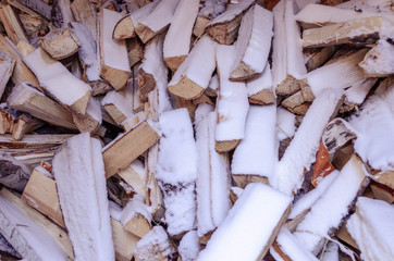 Firewood is stacked in winter. Chopped pile of wood under the snow. Lots of wood. Preparation of firewood for the winter Winter background texture pattern with stacked dry chopped firewood logs covere
