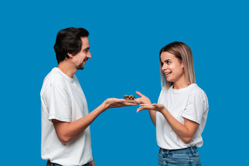 Boyfriend giving present to his girlfriend isolated over blue background. Concept of love