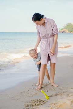 Cheerful kid having fun with mother on beach