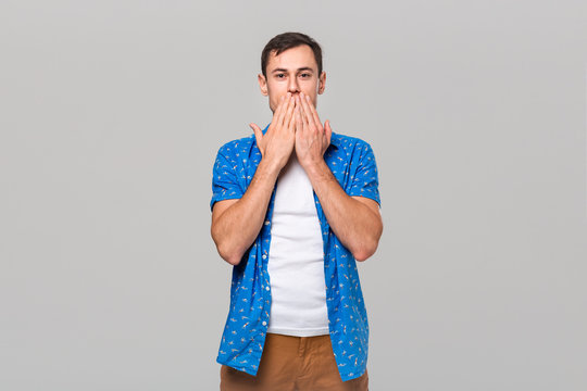 Young man covering mouth with hands. Gesture of three wise monkeys.