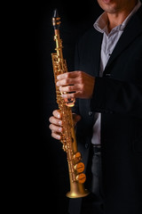 Naklejka premium soprano saxophone in the hands of a guy on a black background