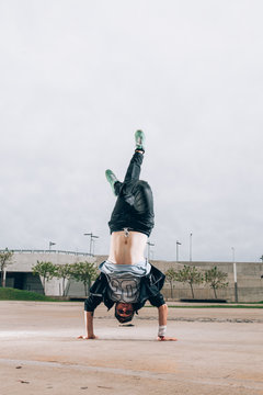 Skillful break dancer performing handstand while moving