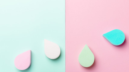 Beauty, make up sponges or beauty blenders in pastel colors on two color background, copy space, top view. Beauty background