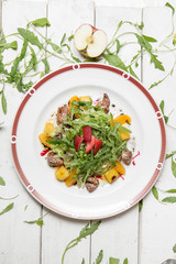 Asian cuisine. Fresh salad with meat, arugula, fruit and strawberries.