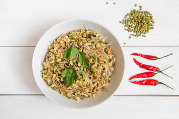 Organic grains good for salads and breads. Raw, vegan, vegetarian healthy food concept. Sprouted wheat seeds with parsley in plate on wooden background.Top view