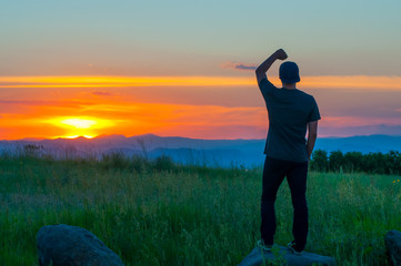 A young person enjoying a sunset over a mountain range