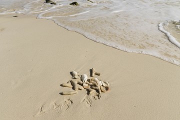 Beautiful seascape view. Shells and fancy pebbles on white sand and turquoise rolling waves on background. Atlantic ocean. 