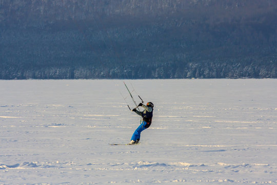 snowkiting extreme winter sport. athletes on a wild winter mountain lake in the evening at sunset ride. fresh white snow and wind.