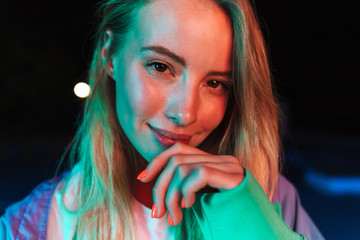 Image of woman looking at camera over bright neon lightening at night