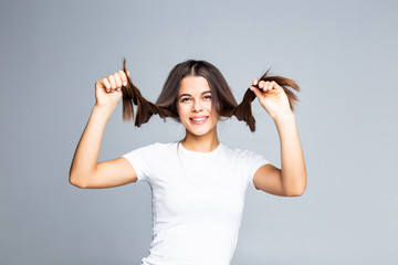 Cute young girl playing with her hair isolated on gray background