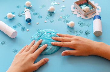 a girl making slime herself. child making slime on blue Christmas background. 