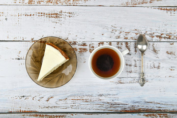 Cheesecake with coffee on a light wooden background. Coffee in a coffee shop, copy space. New York cheesecake on a light concrete background, top view. Classic cheesecake and a cup of coffee.