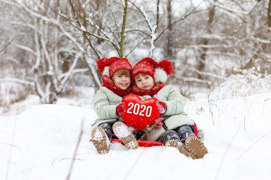 Twin sisters show heart with the numbers new 2020 year.