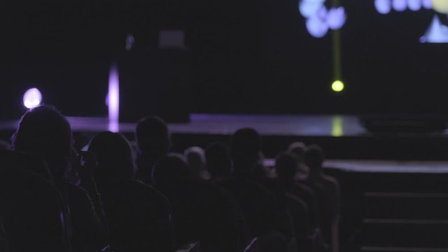 Visitors to a business forum watch a presentation on the screen