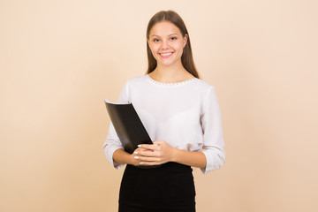 beautiful young woman on a beige background with a folder in her hands