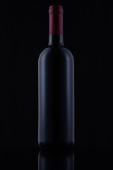 Black glass bottle of red wine on black background