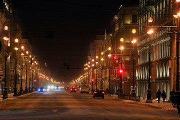 traffic of cars and pedestrians on a winter city street illuminated by lanterns