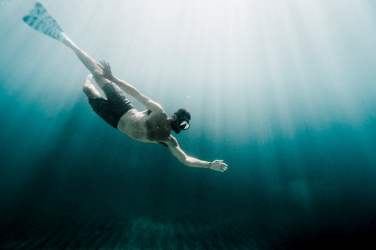 Man Swimming Underwater In Ocean