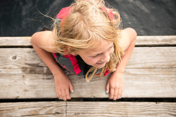 Child Smiling While Swimming at a Lake near a Dock